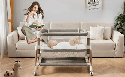 maman assis sur le canape entrain de lire un livre pendant que son bebe est tranquillement allonger dans son cododo a cote