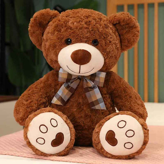 doudou ours marron assis avec un nœud de papillon autour du cou