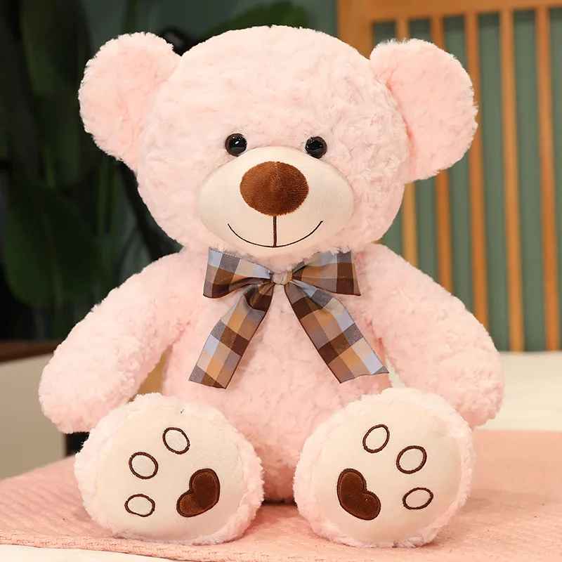 doudou ours rose pale assis avec un nœud de papillon autour du cou