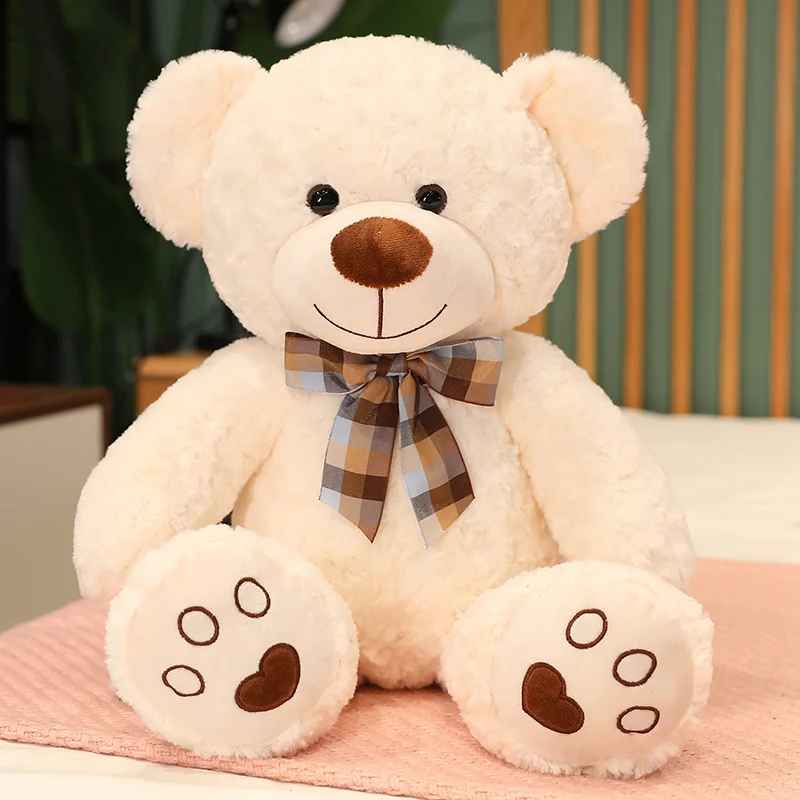 doudou ours écru assis avec un nœud de papillon autour du cou
