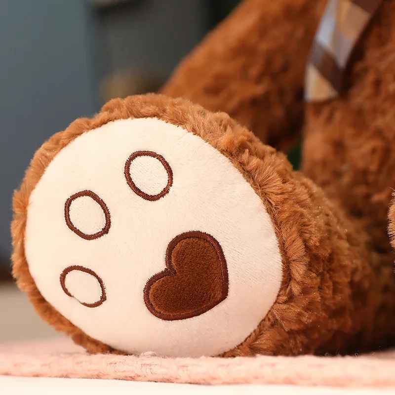 doudou ourson qui montre en gros plan le sous pied la patte avec un petit cœur