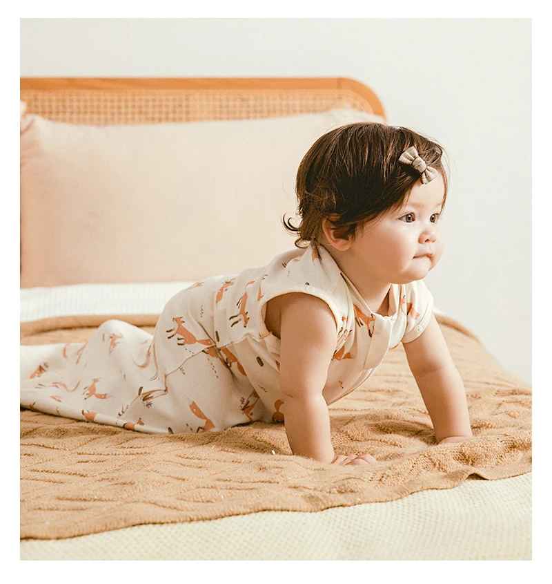 petite fille a quatre pattes sur le lit de ces parents avec sa gigoteuse renard