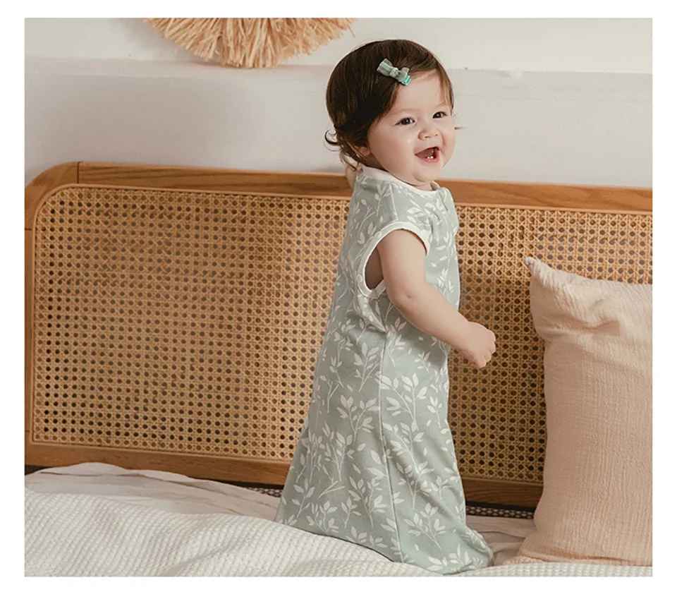 petite fille debout se tenant au lit avec sa gigoteuse sur elle