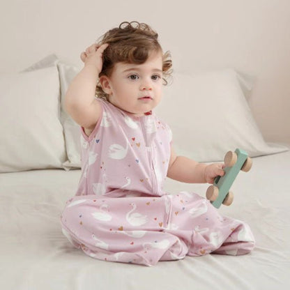 petite fille assise sur le lit avec sa gigoteuse fermer sur elle avec un jouet dans la main