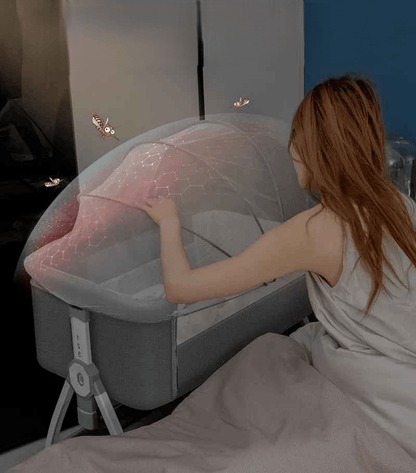lit cododo maman qui surveille son bebe dans la nuit qui es protéger avec une moustiquaire