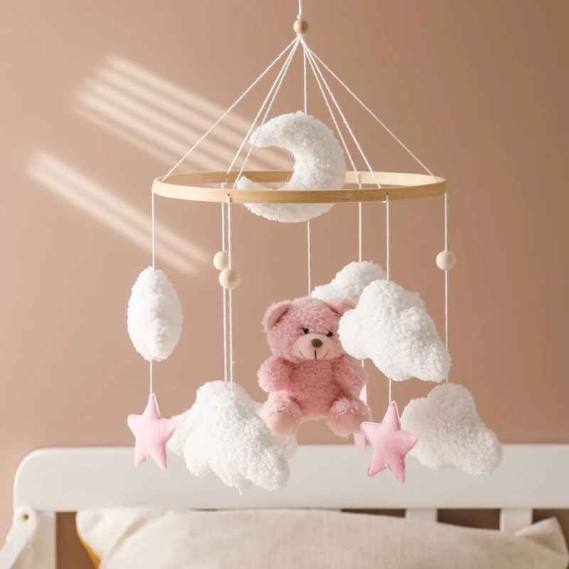 mobil pour lit bebe suspendu au dessus du lit a barreau avec le nounours rose et blanc