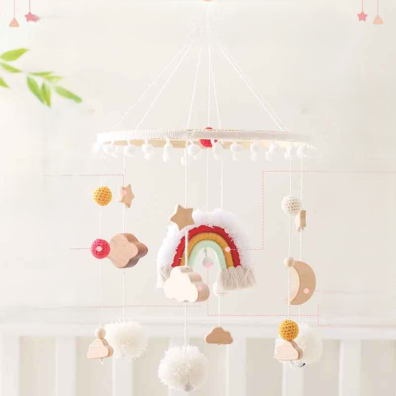 mobile bebe pour lit avec un arc en ciel des petites boule jaune rouge des pompons blanc et des objets en bois